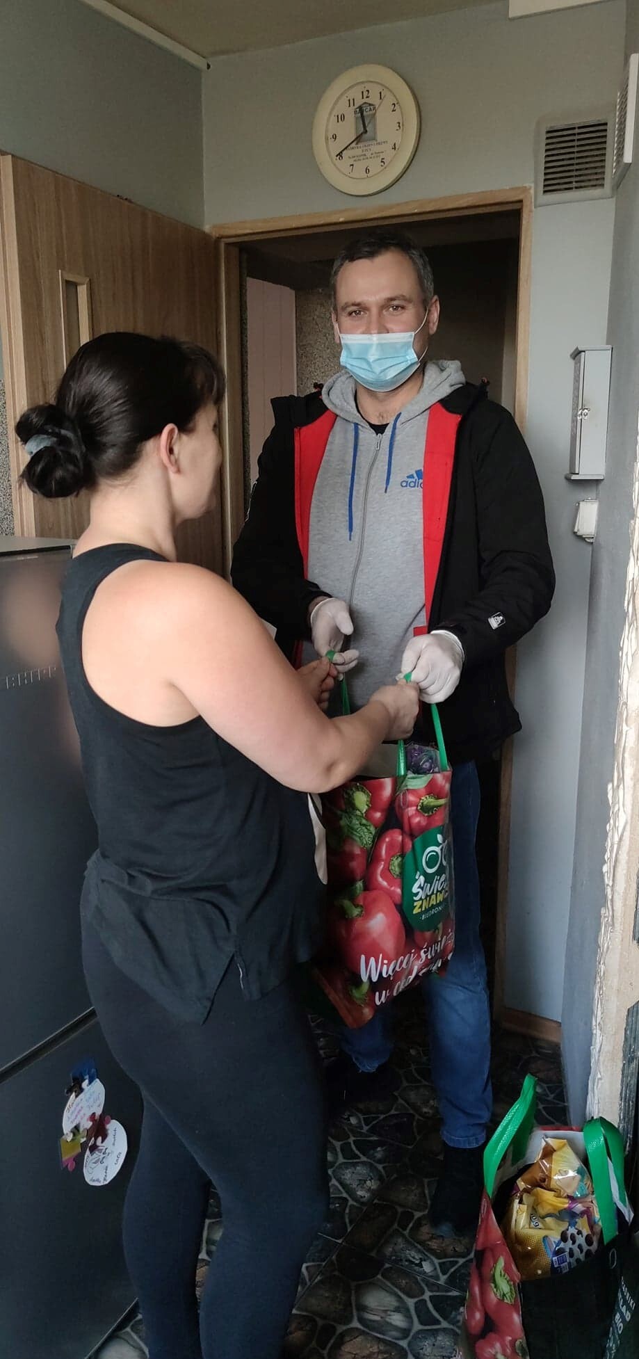 pracownik ośrodka pomocy społecznej przekazujący paczkę żywnościową