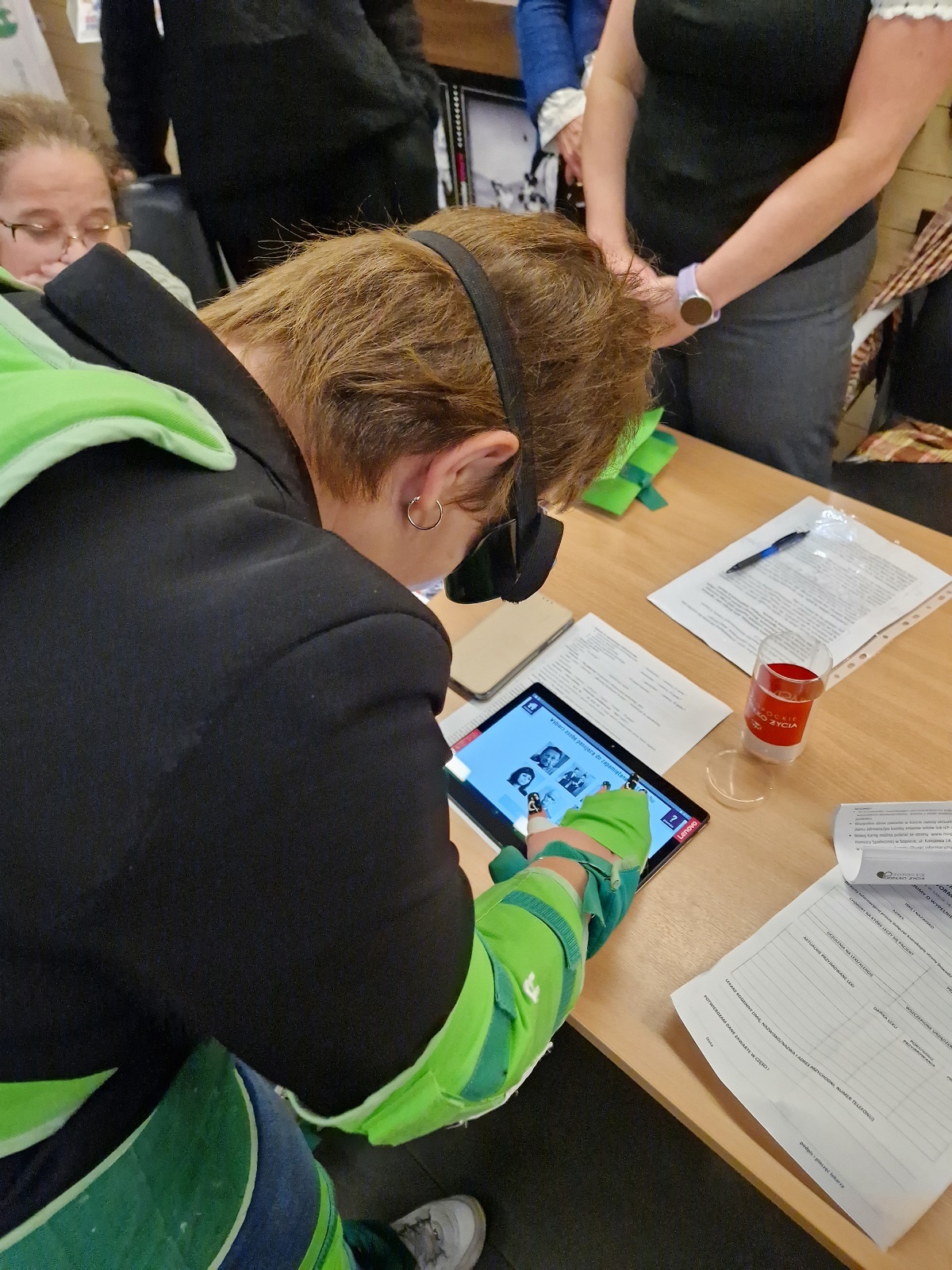 zdjęcie przedstawia uczestniczkę kongresu pochyloną nad stołem, na którym leży tablet