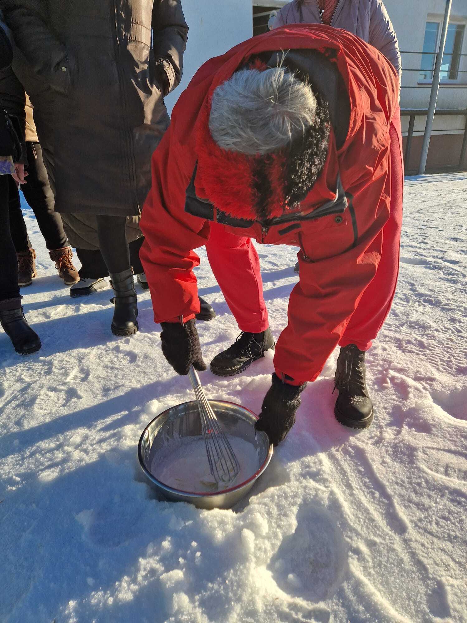 uczestniczka warsztatów ubijająca na śniegu w metalowej misce deser lodowy