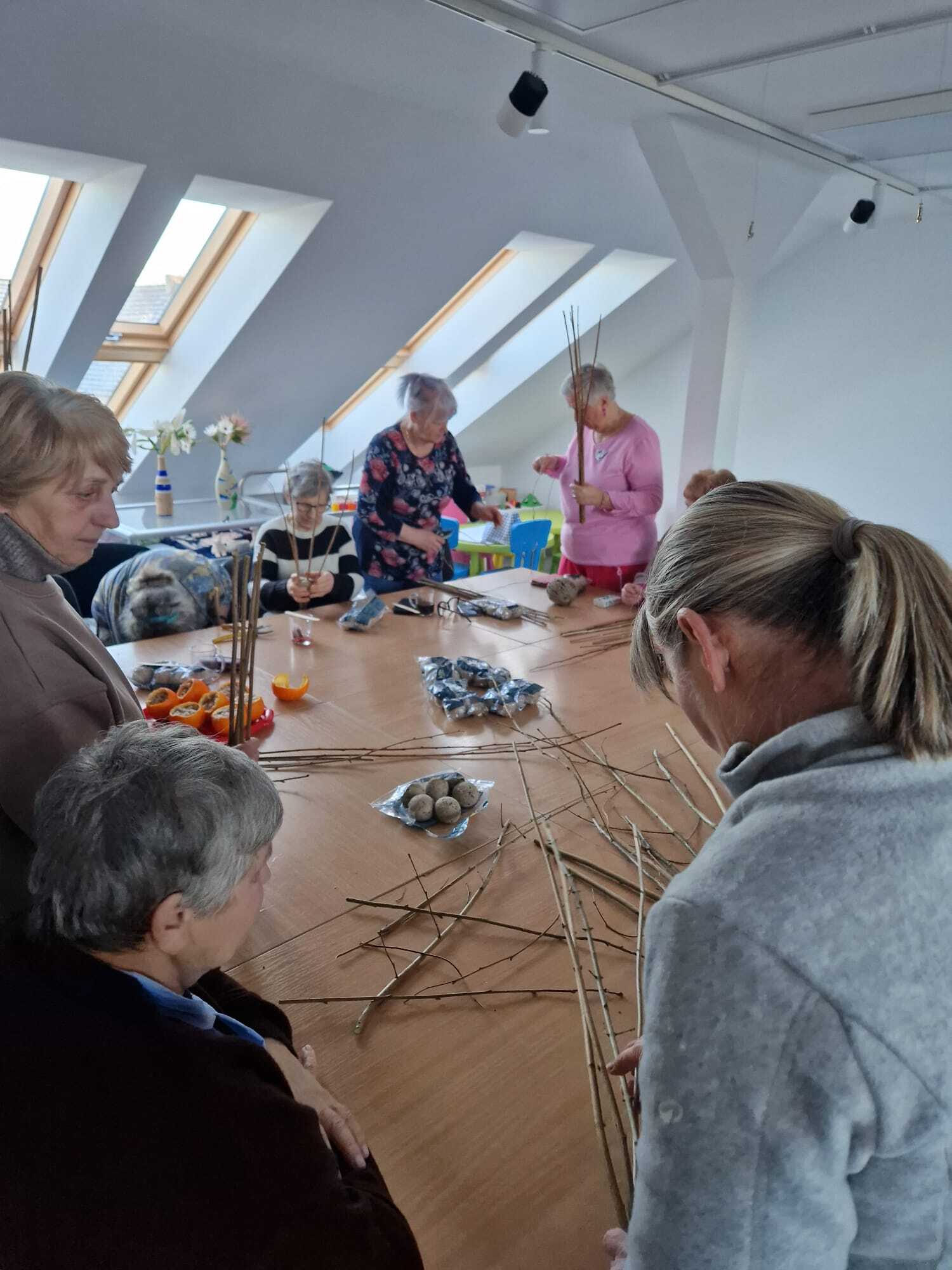 siedem uczestniczek warsztatów przy dużym wspólnym stole tworzące karmniki dla ptaków