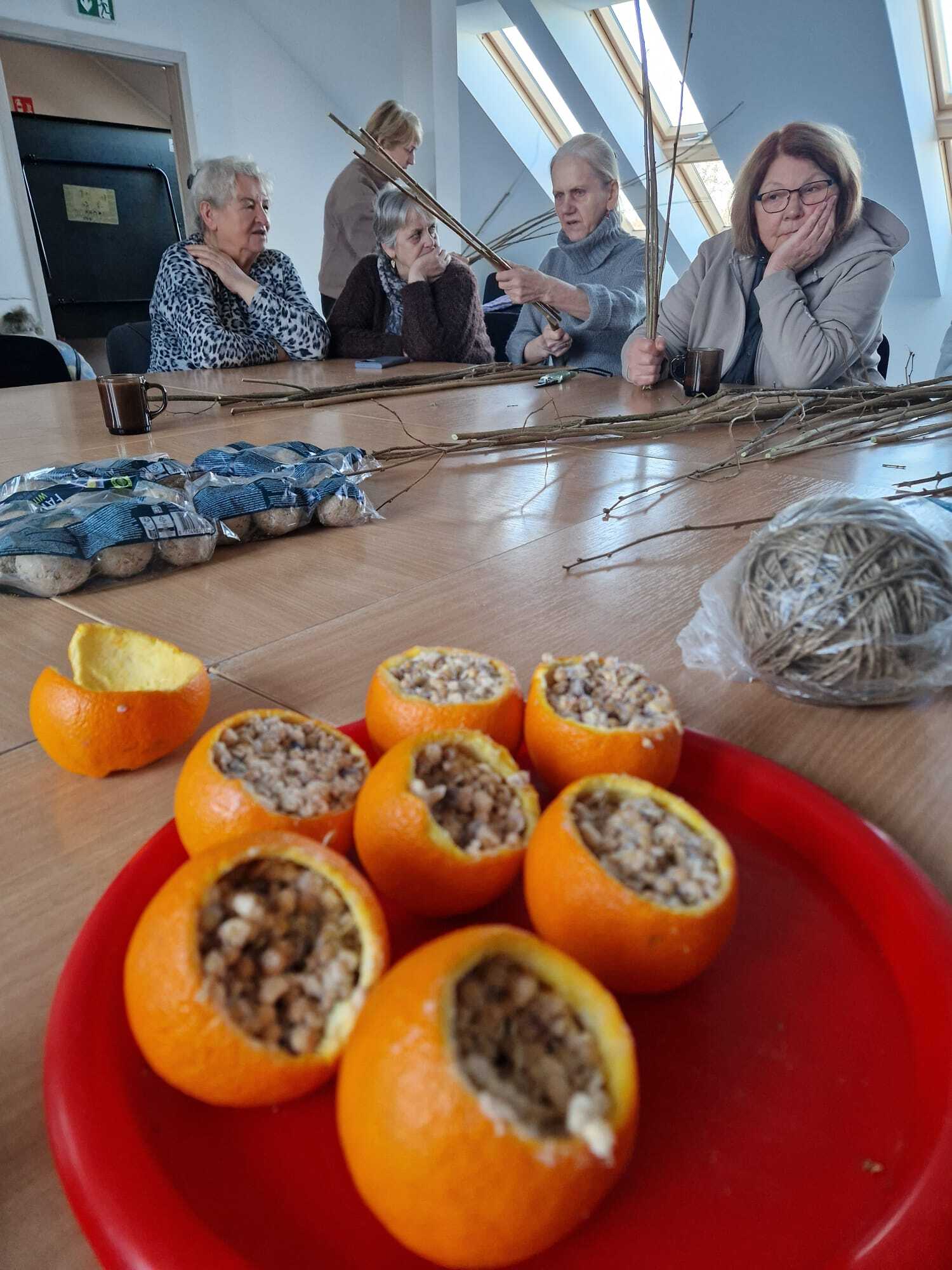 pięć uczestniczek warsztatów przy stole budujące karmniki dla ptaków