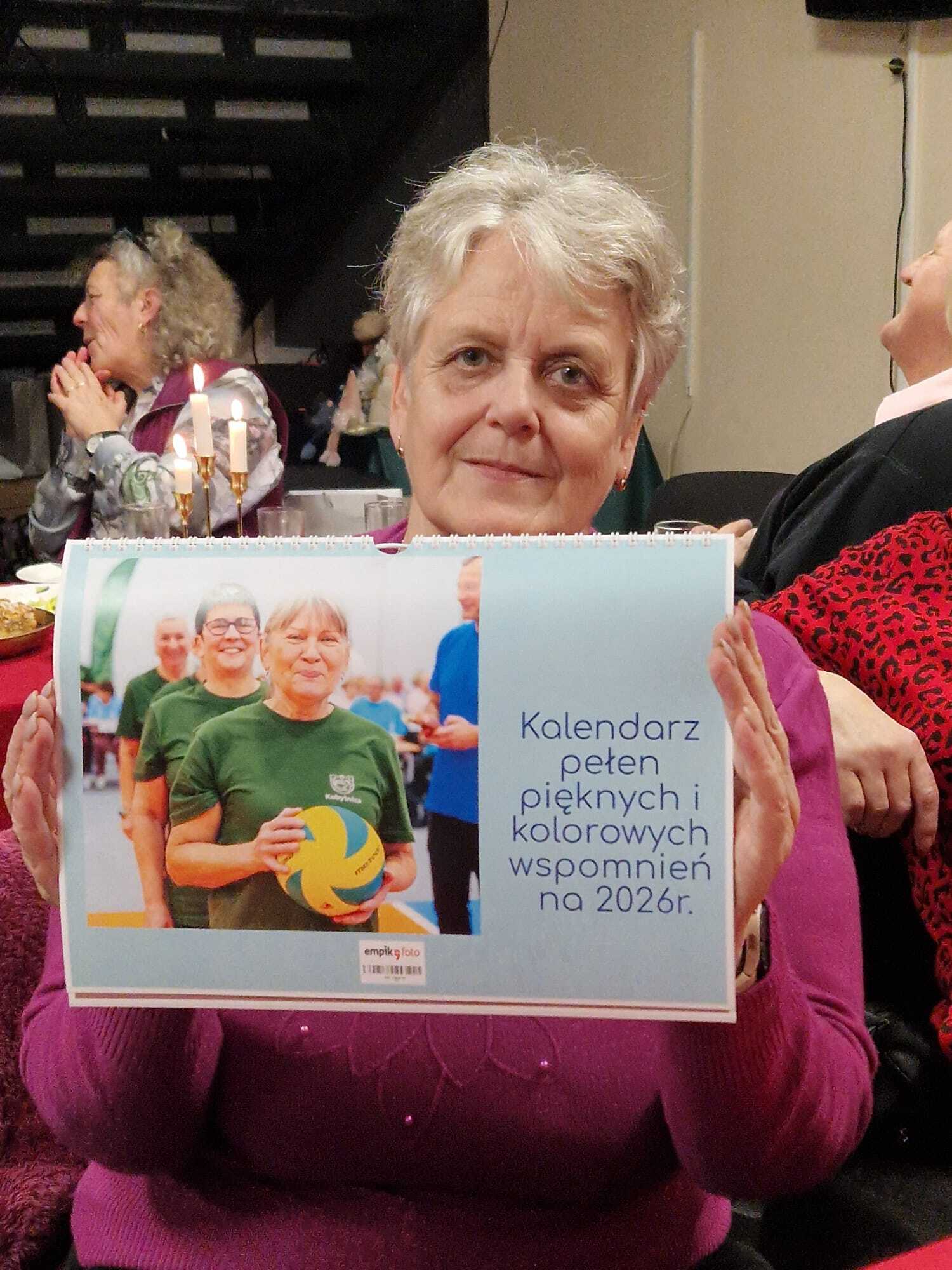 uczestniczka Klubu Seniora prezentująca kalendarz pełen pięknych i kolorowych wspomnień na 2026 rok