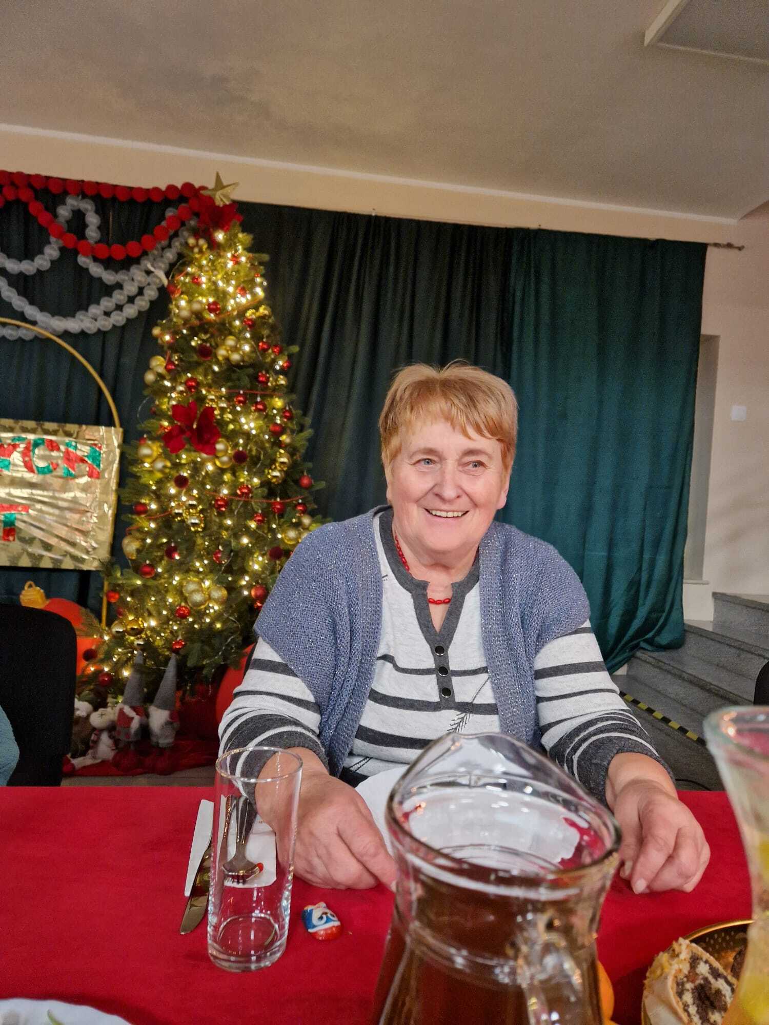 uśnmiechnięta uczestniczka spotkania siedząca przy stole mikołajkowym