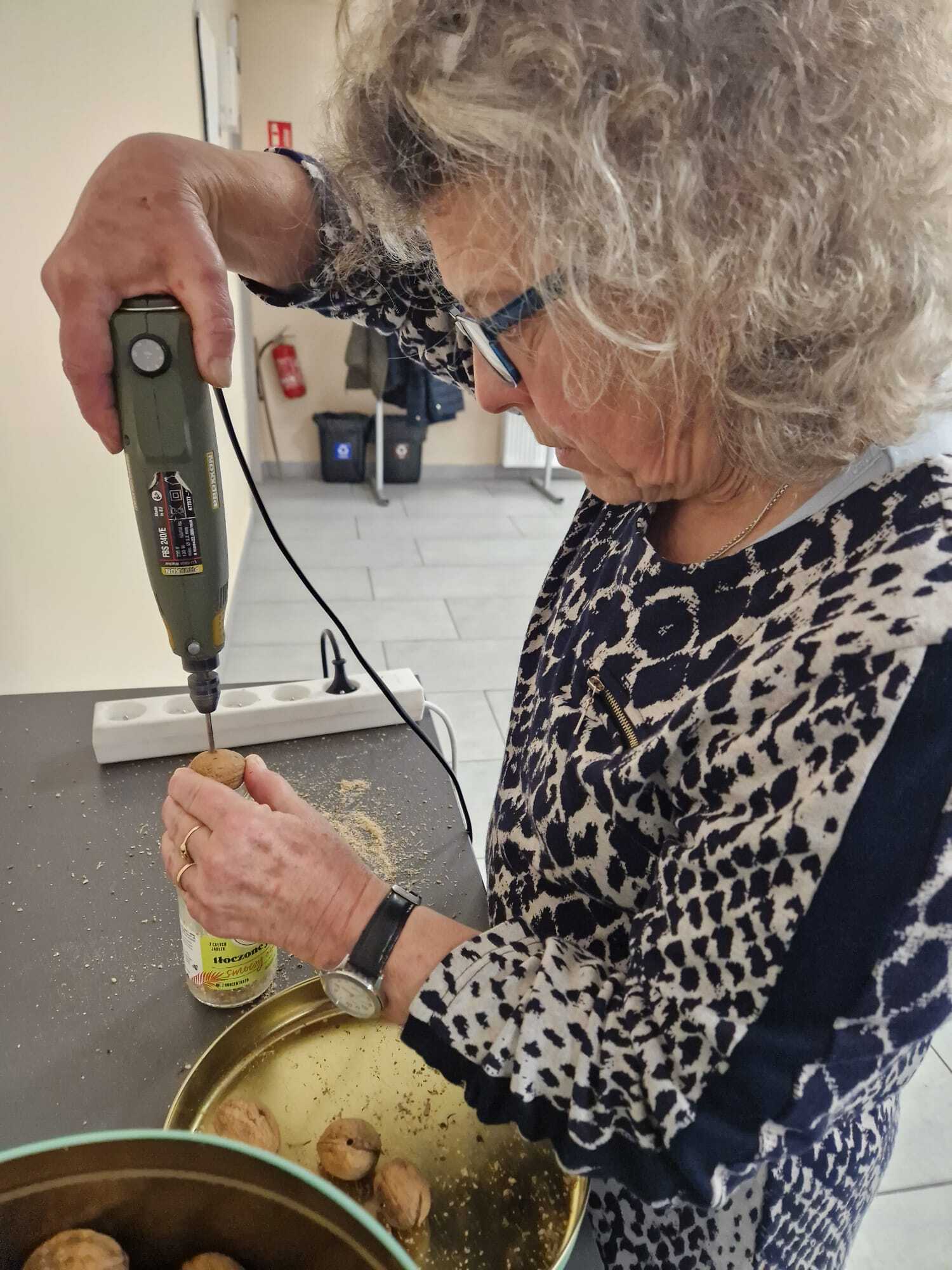 uczestniczka warsztatów wiercąca otwór w orzechu włoskim