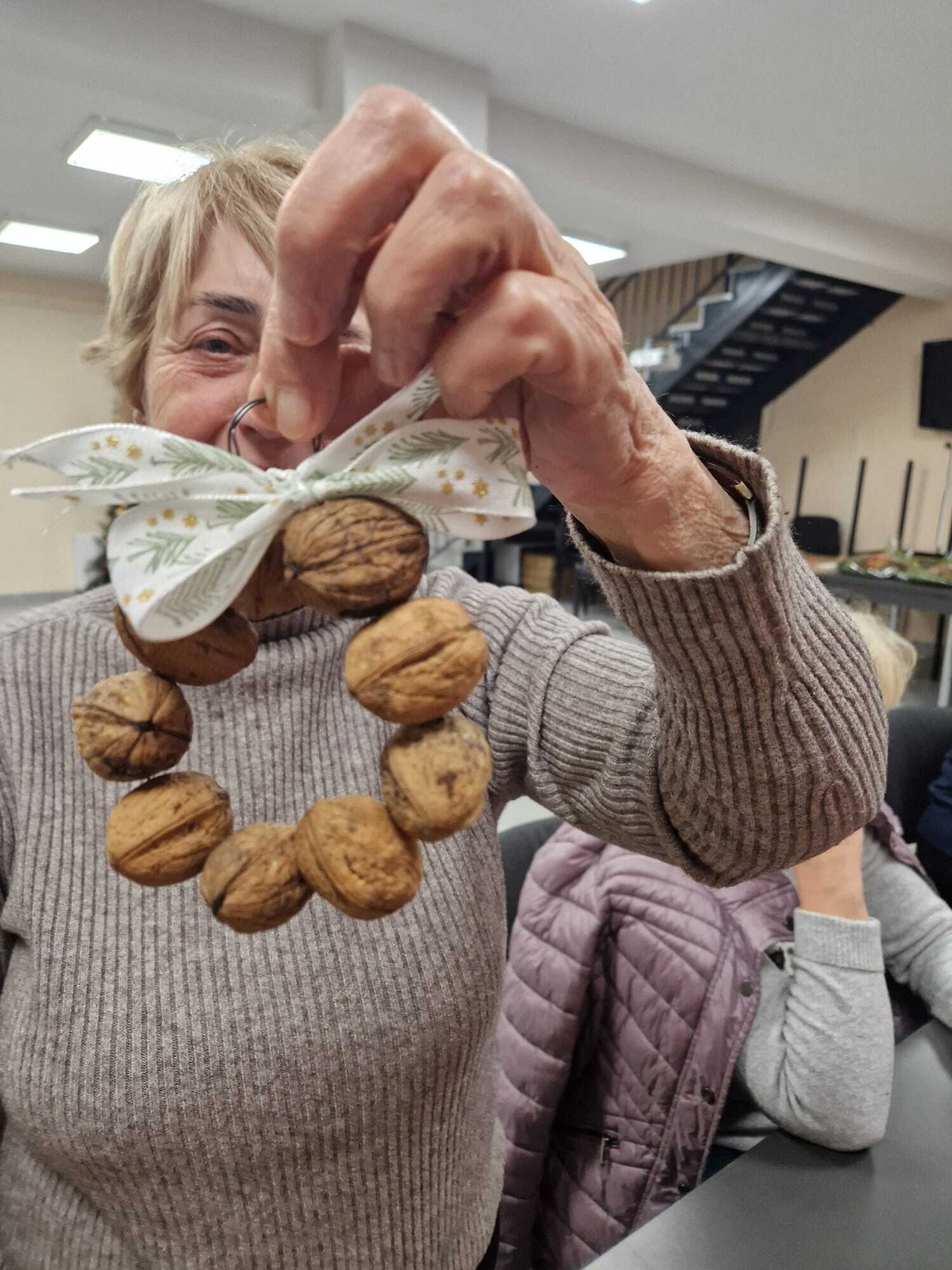 uczestniczka warsztatów prezentująca w dłoni gotową ozdobę z orzechów włoskich
