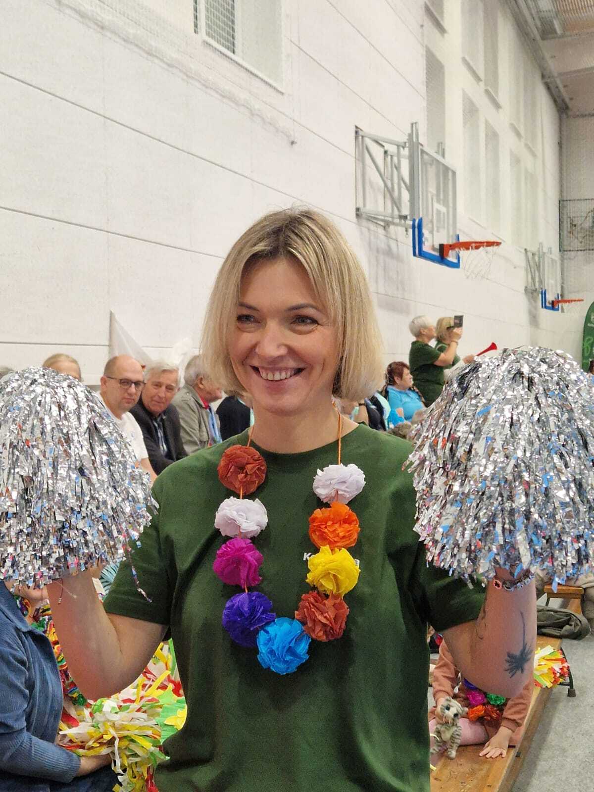 zdjęcie przedstawia kibicującą uśmiechniętą panią Burmistrz Annę Gliniecką - Woś z pomponami w dłoniach