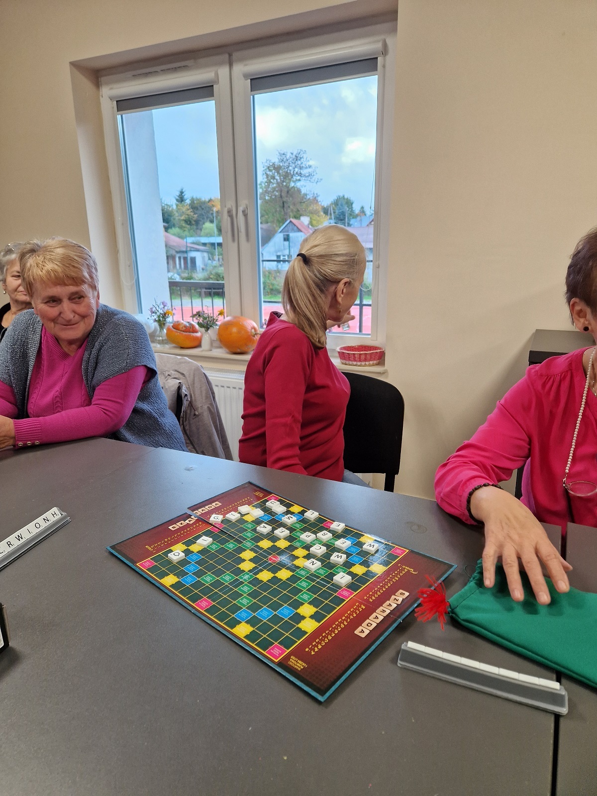 zdjęcie przedstawia cztery uczestniczki spotkania przy stole, na którym leży gra planszowa