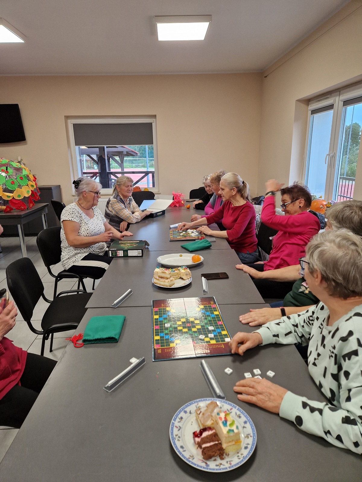 zdjęcie przedstawia uczestniczki spotkania siedzące przy wspólnym stole i grające w planszówki