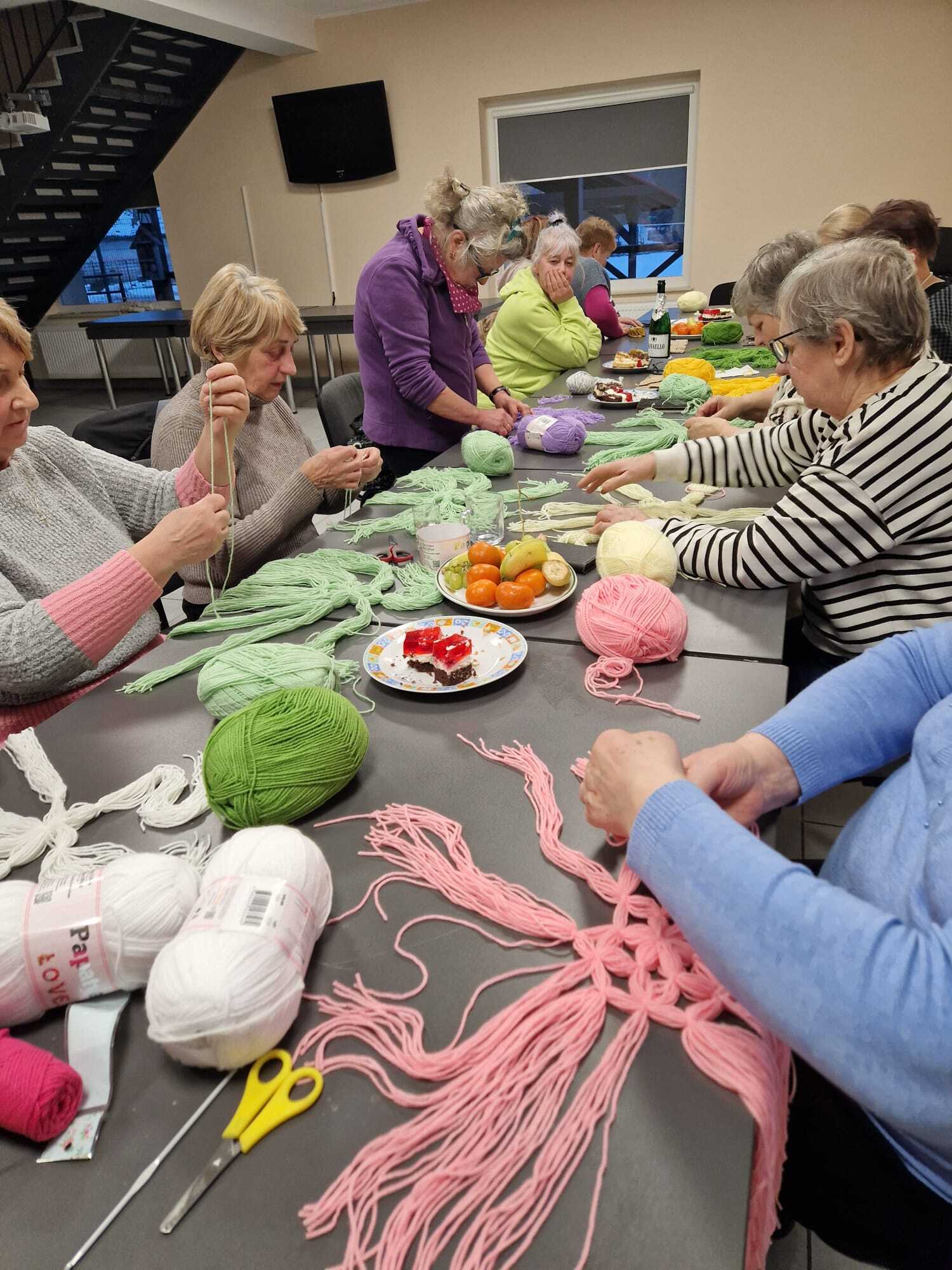 uczestniczki warsztatów siedzące przy stole wykonujące ozdoby z włóczki