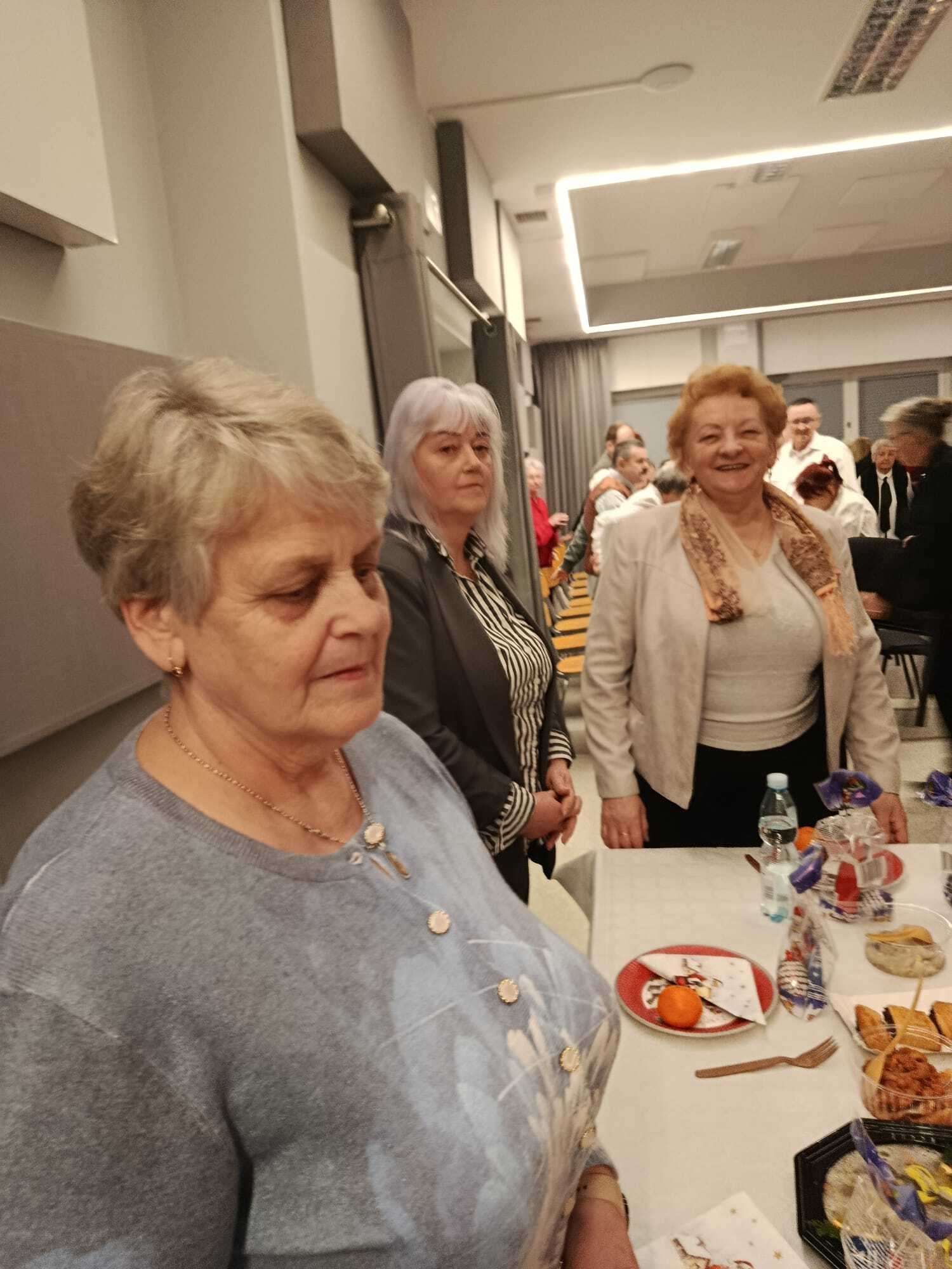 trzy uczestniczki spotkania wigilijnego stojące przy wspólnym stole