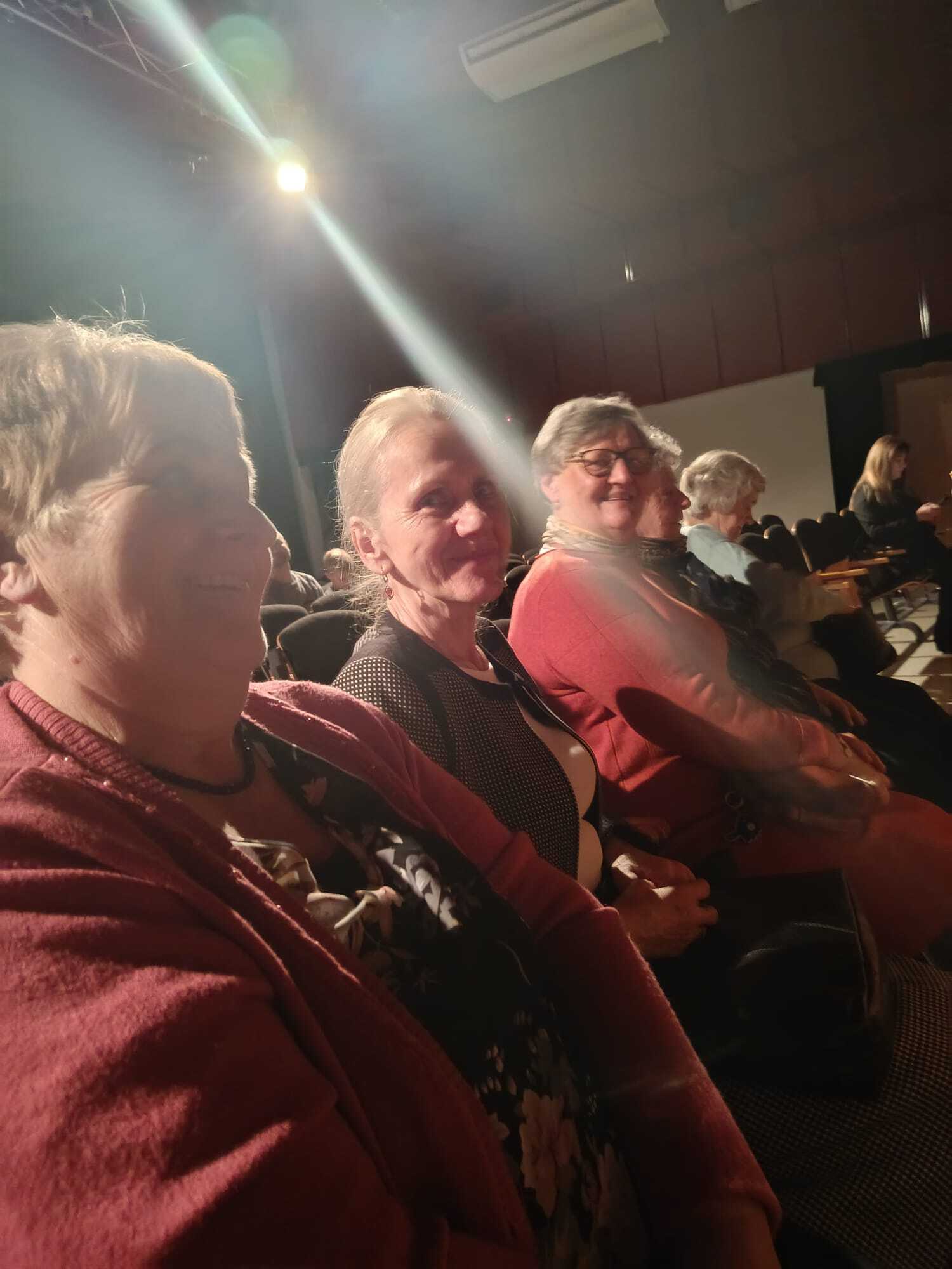 trzy uczestniczki spotkania wigilijnego siedzące na widowni sali teatralnej podczas jasełek