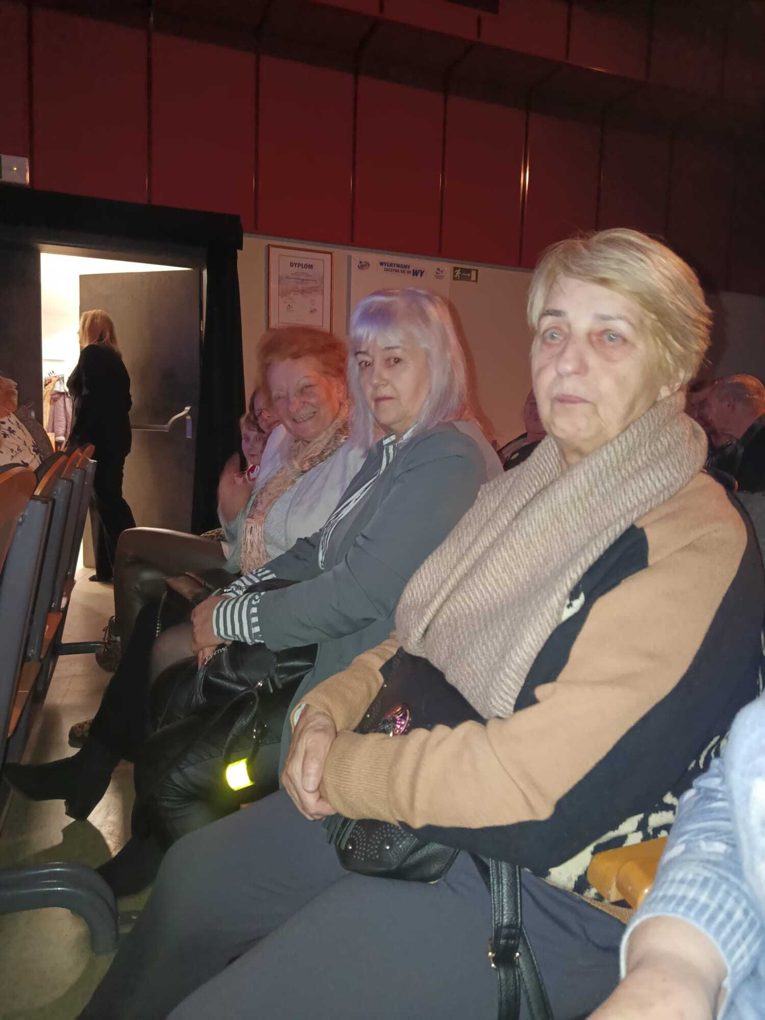 trzy uczestniczki spotkania wigilijnego siedzące na sali teatralnej podczas jasełek