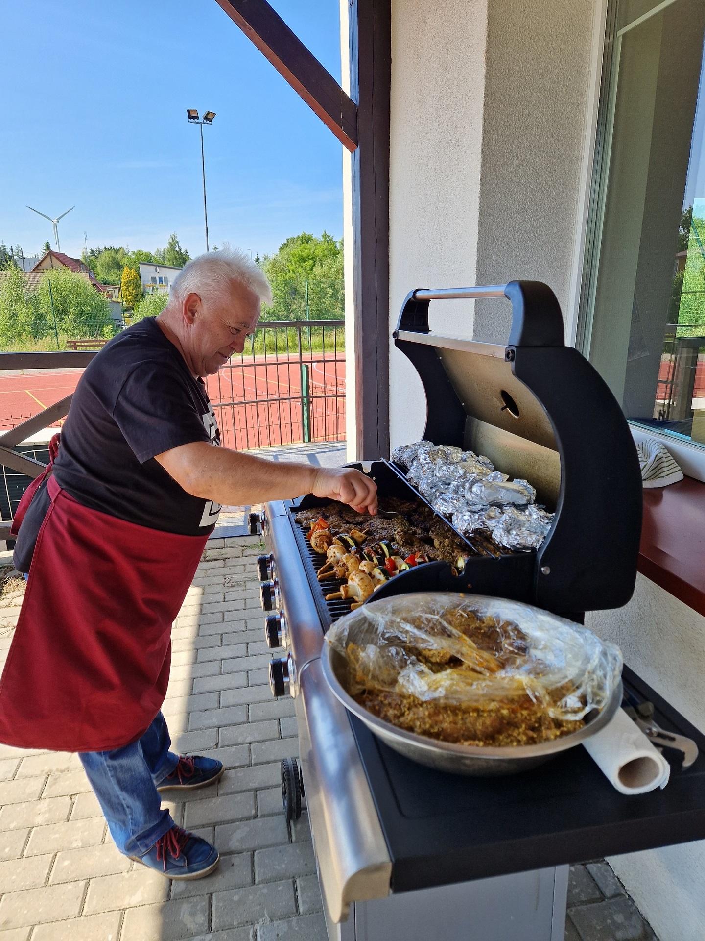 uczestnik warsztatów doglądający potraw na grillu