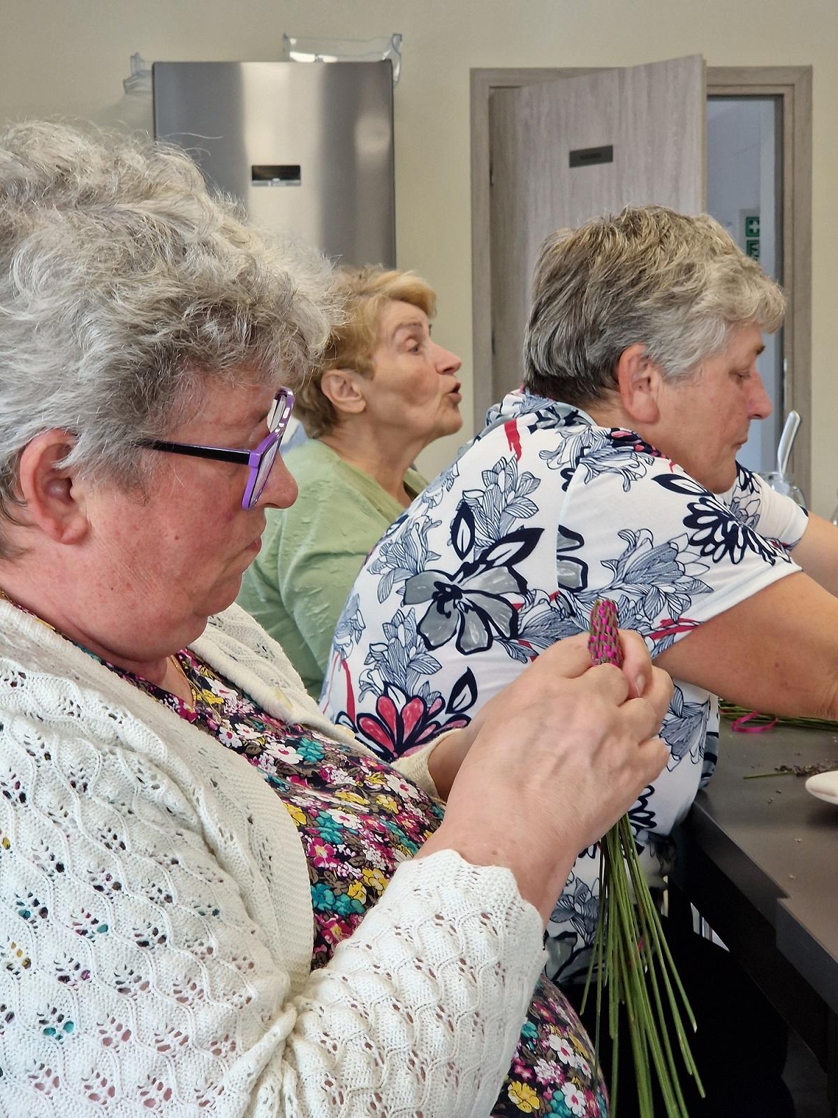 trzy uczestniczki spotkania siedzące przy stole warsztatowym