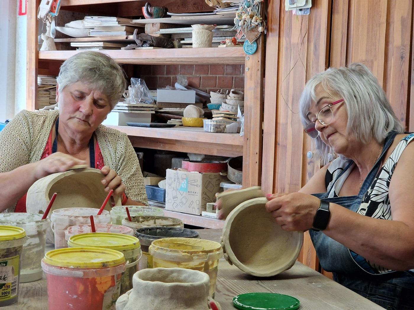 dwie uczestniczki warsztatów przygotowujące wykonane misy do ceramikowania