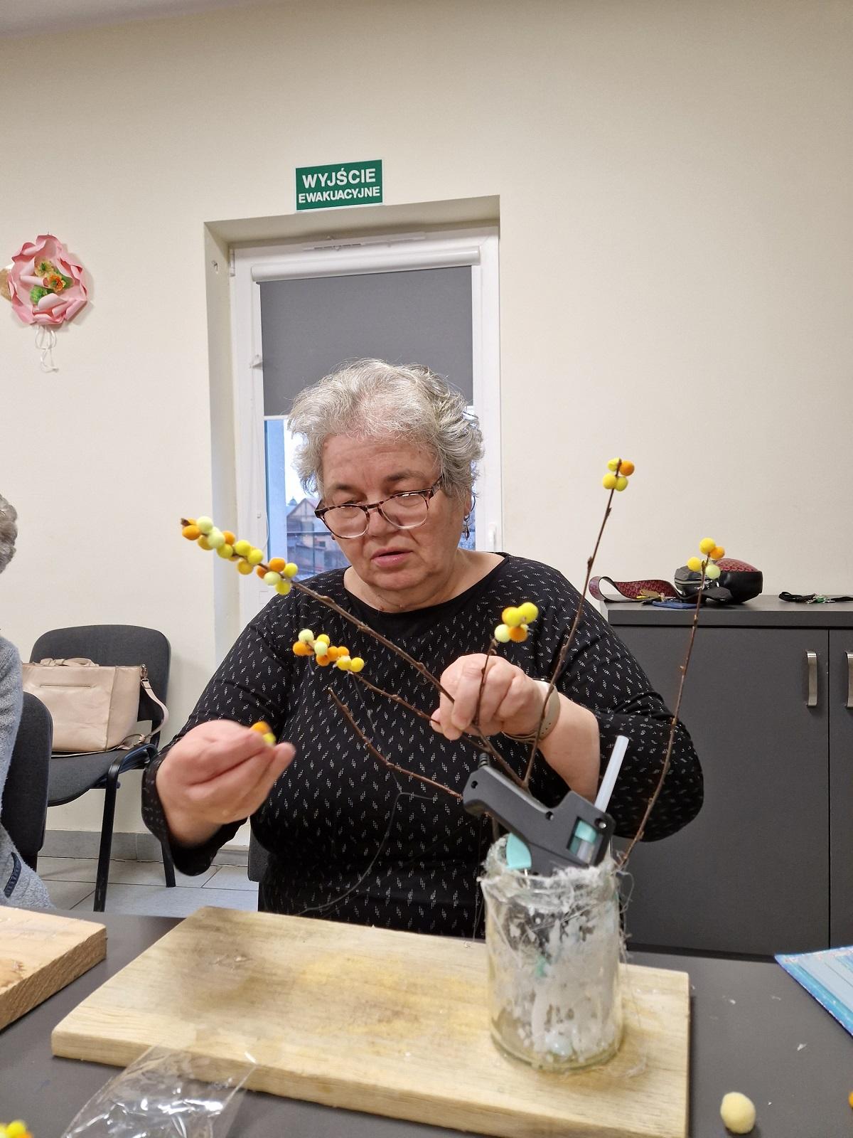 uczestniczka warsztatów wykonująca gałązkę kwitnącej mimozy