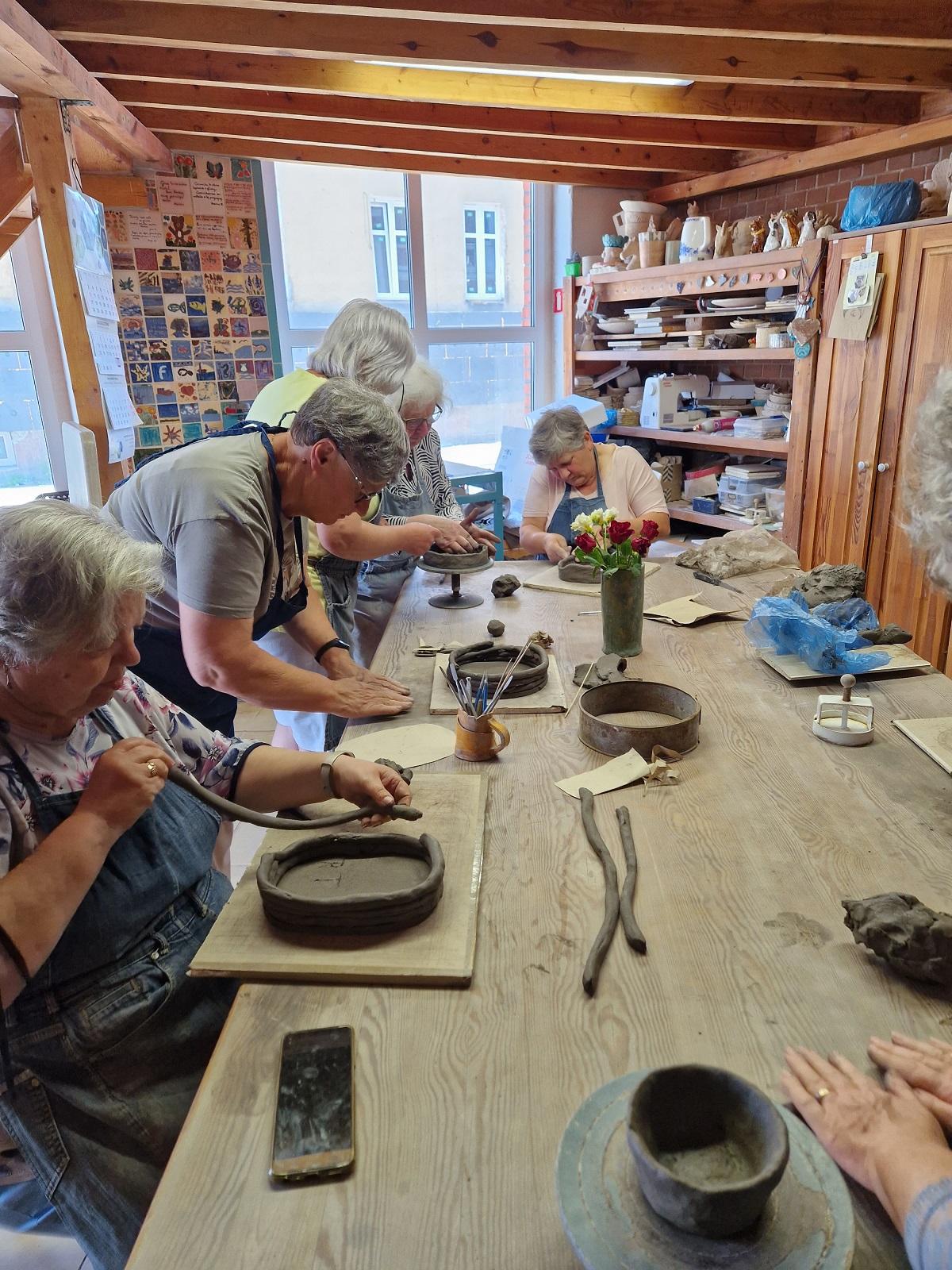 uczestniczki warsztatów przy stole wykonujące prace ceramiczne